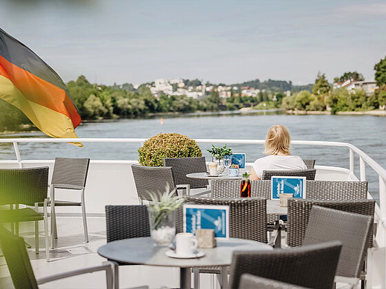 Eine Frau sitzt am Obereck an einem Tisch und blickt auf die Donau