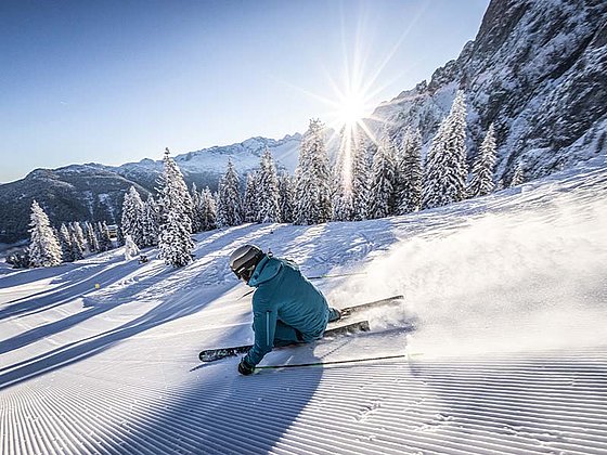 ein Skifahrer auf der frisch präparierten Piste bei Sonnenschein
