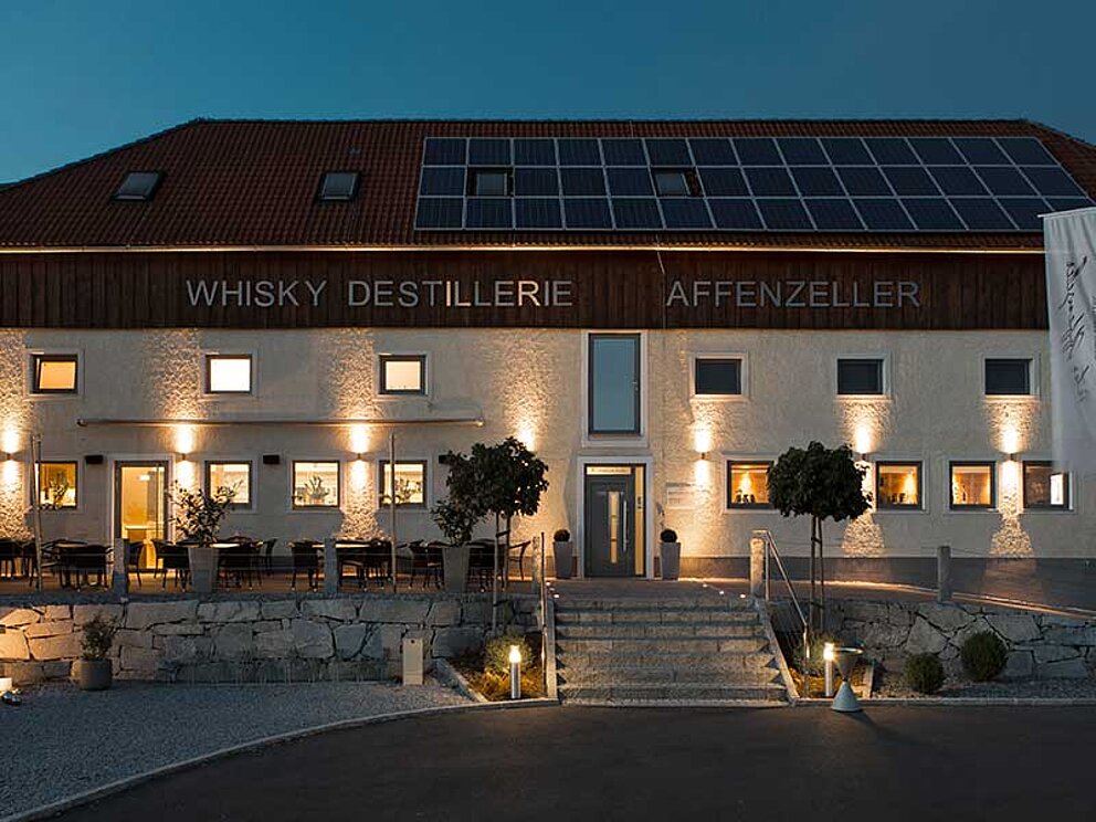 das beleuchtete Gebäude der Whisky Destillerie Affenzeller in Alberndorf