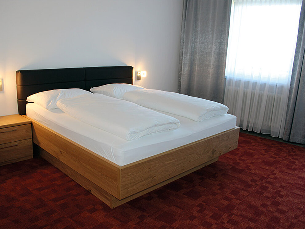 Zimmer mit Doppelbett und Teppichboden.