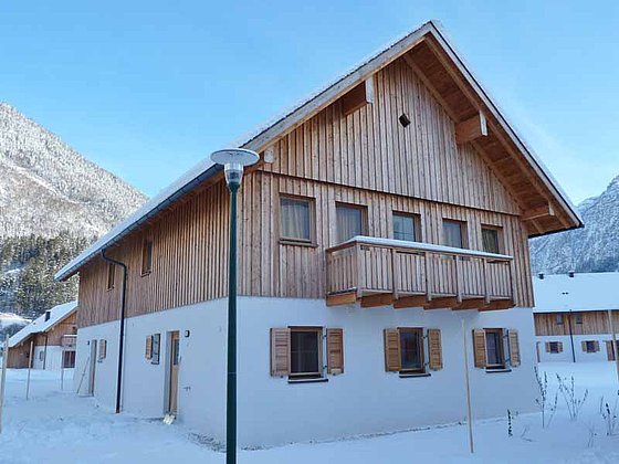 Ferienhaus im Schnee mit Holzfassade, Balkon und Fensterläden
