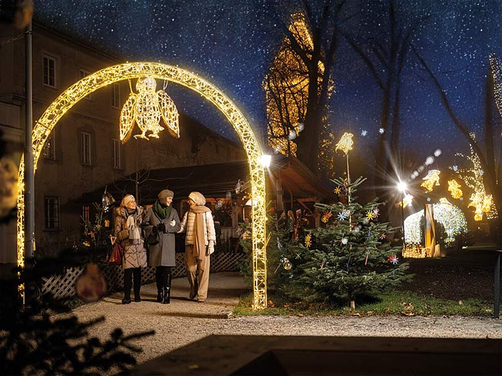 Besuch beim Welser Adventmarkt - Leute stehen unter beleuchteten Bogen beim Pollheimerpark