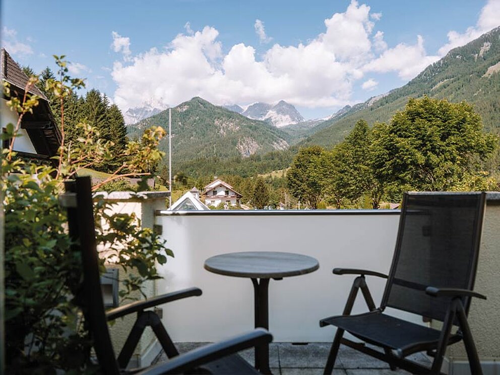 Balkon mit 2 Stühlen und Tisch, im Hintergrund Berpanorama