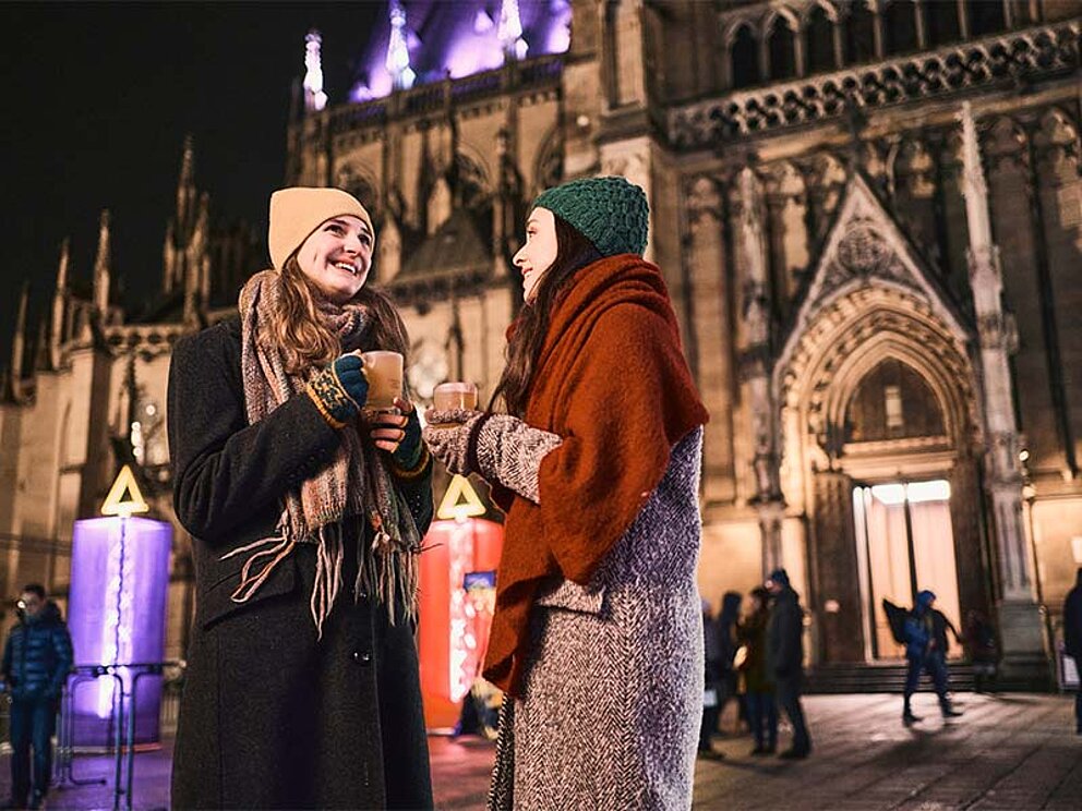 2 Damen mit Punschtasse vor dem Linzer Dom am Abend