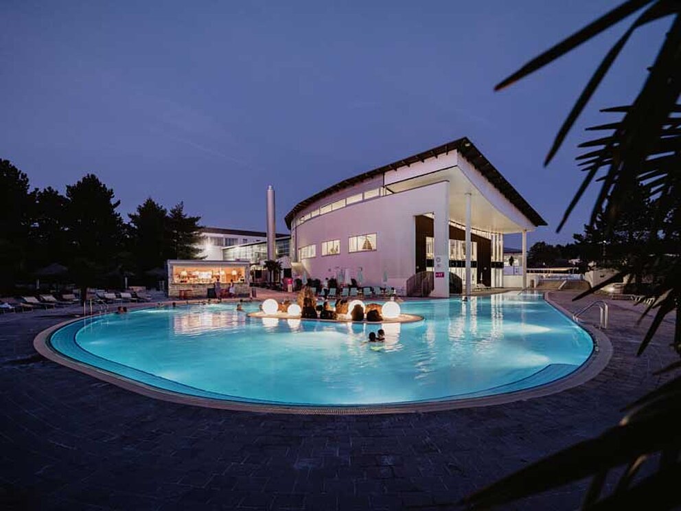 Das Außenbecken im Spa Resort Geinberg ist in der Nacht beleuchtet
