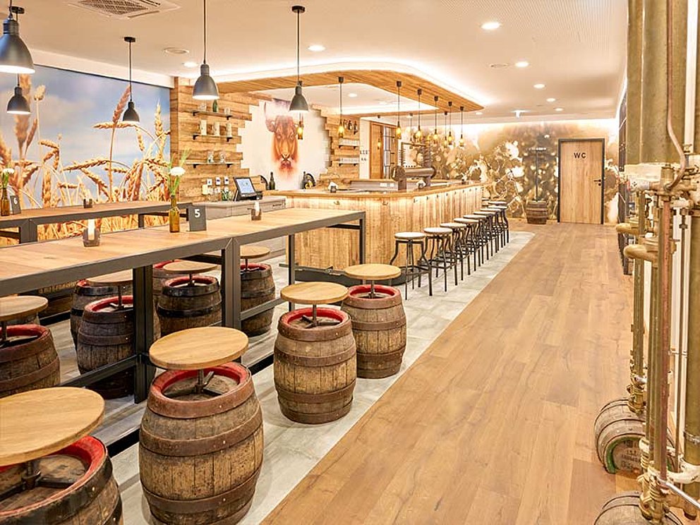 Stehtische mit alten Fässern als Hocker, eine Bar
