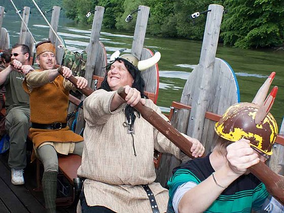 als Wikinger verkleidet sitzen die Teilnehmer an den Ruderbänken am Wikingerschiff auf der Donau