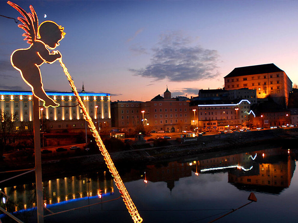 Blick von der Nibelungenbrücke auf die beleuchtete Stadt in der Abenddämmerung