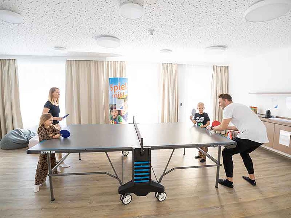 Eltern mit Kindern spielen Tischtennis im Dormio Aparthotel