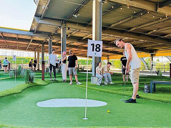 Eine kleine Gruppe beim Minigolfspielen am Loch 18.