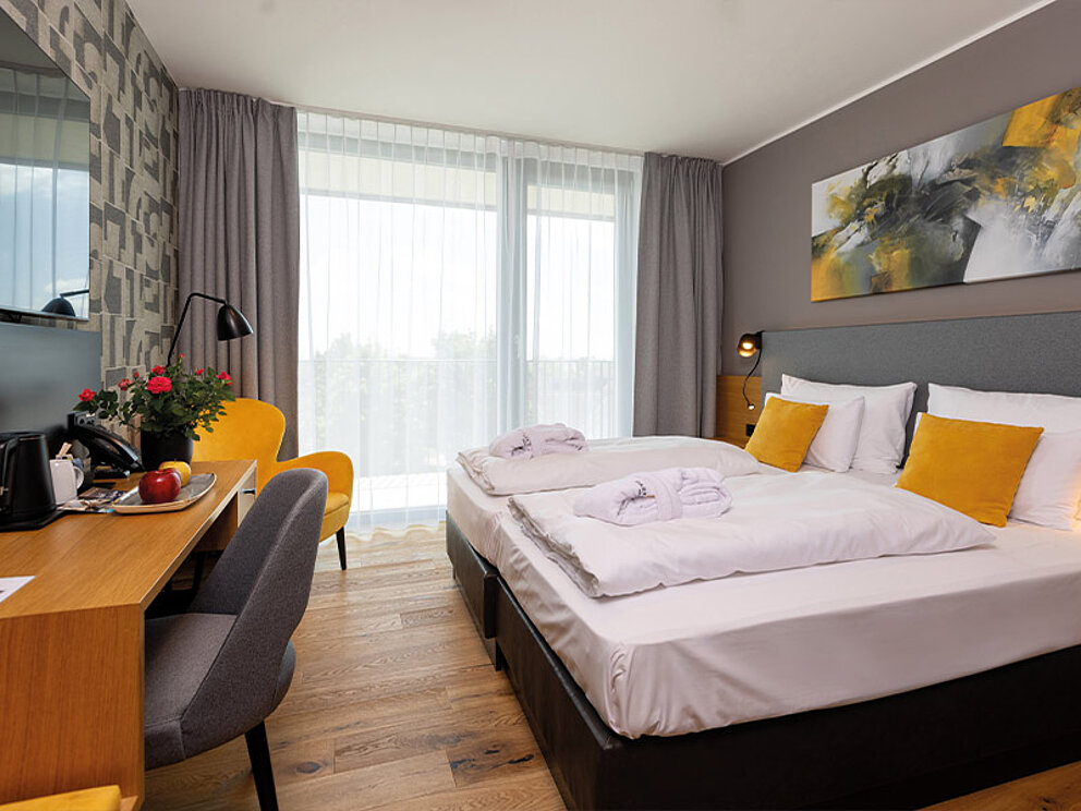 Doppelzimmer mit Holzboden, Doppelbett, Bademänteln, Schreibtisch und TV