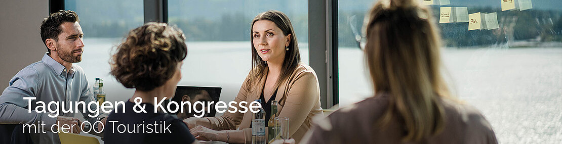 4 Personen sitzen am Tisch bei einer Business-Tagung
