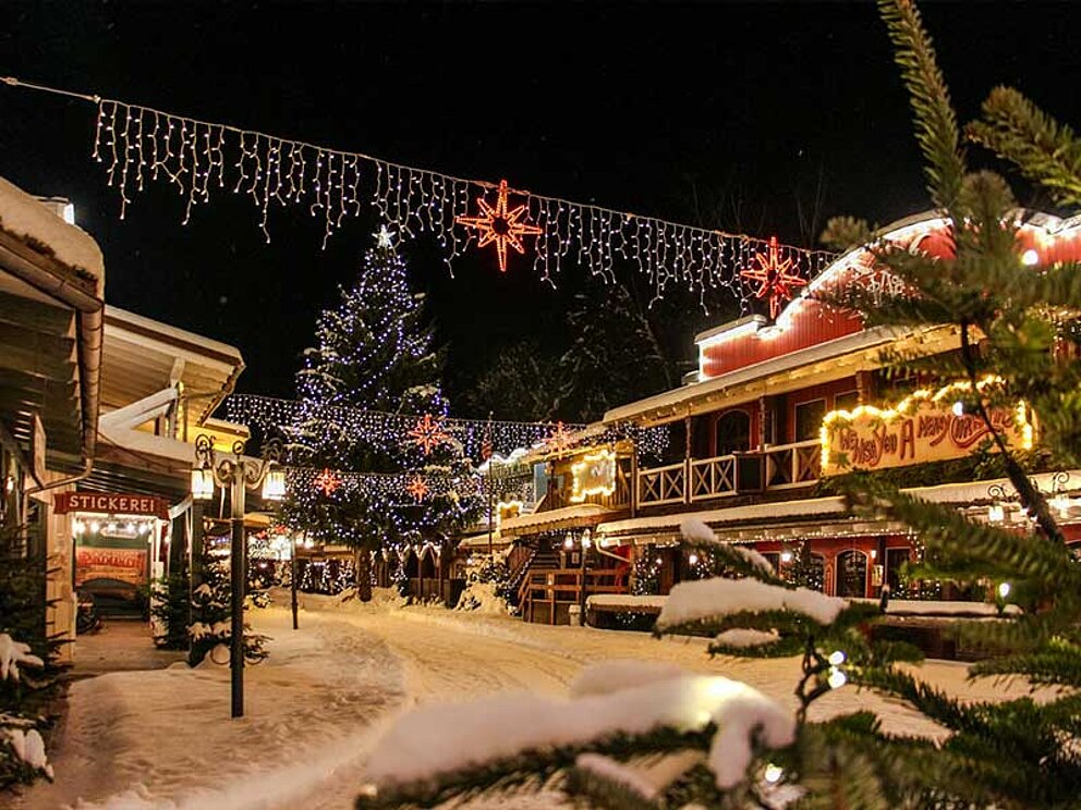 Verschneite Westernstadt in der Nacht mit viel Weihnachtsbeleuchtung