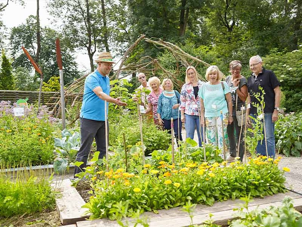 ein Gruppe mit Guide bei blühenden Blumenbeeten