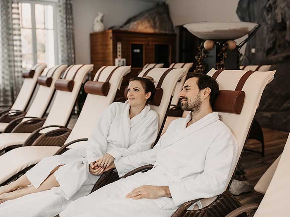 Paar im Bademantel auf Ruheliegen im Wellnessbereich