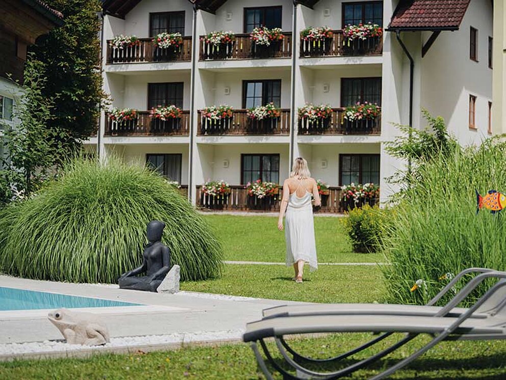 Gartenansicht mit einer Dame mit Handtuch, Außenansicht des Hotels.