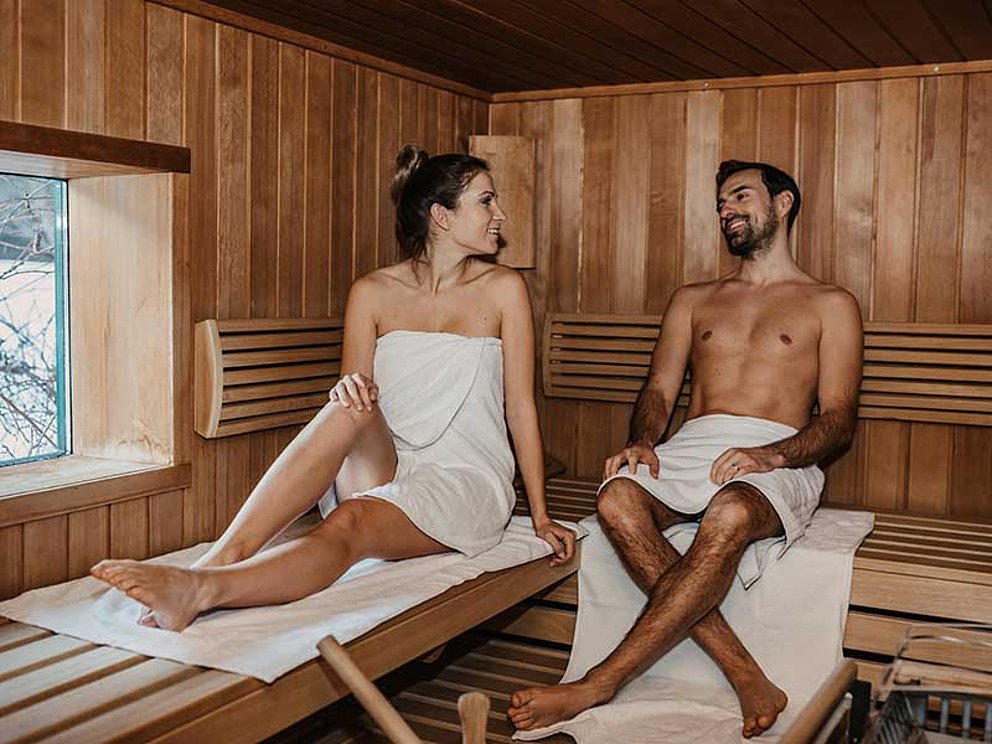 Paar in der Hotelsauna, eingehüllt in Badetücher