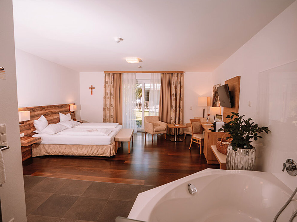 Doppelzimmer mit Doppelbett und freistehender Badewanne