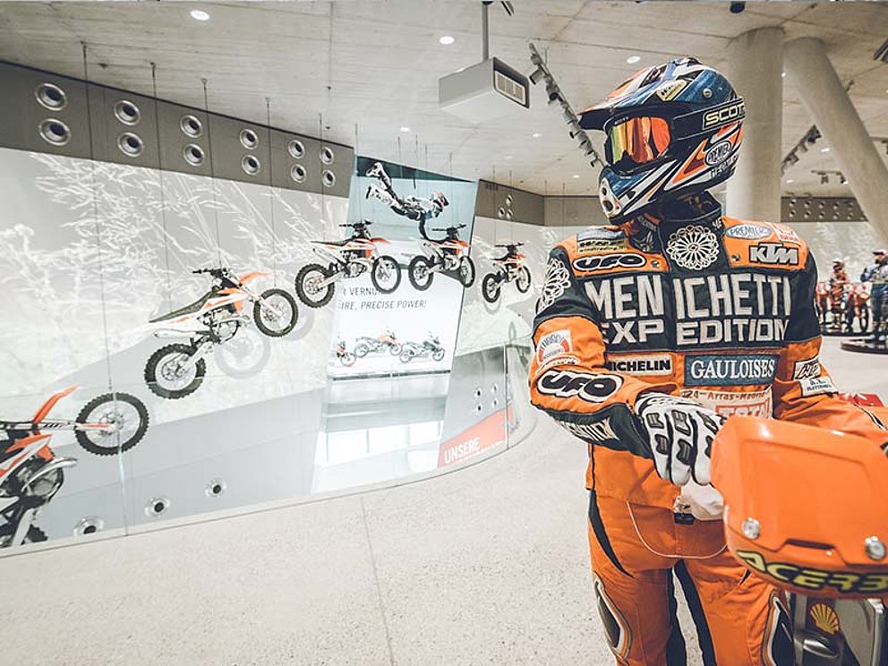 Laufbahn eines Moto-Cross Spunges, im Vordergrund die Darstellung eines Moto-Cross-Fahrers in Motorrad-Kleidung