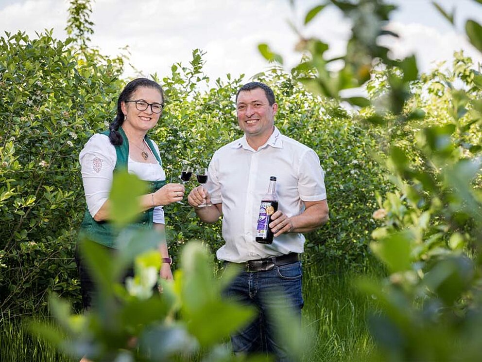 das Paar Froschauer im Aronia-Garten prostet sich mit einem Glas Aronia-Schnaps zu