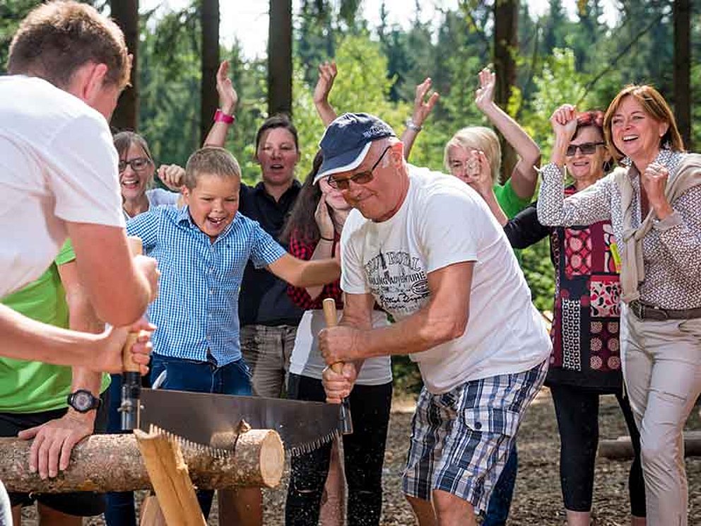 lustiges Gruppenspiel mit Holzsägen bei der Holzfällergaudi am Baumkronenweg