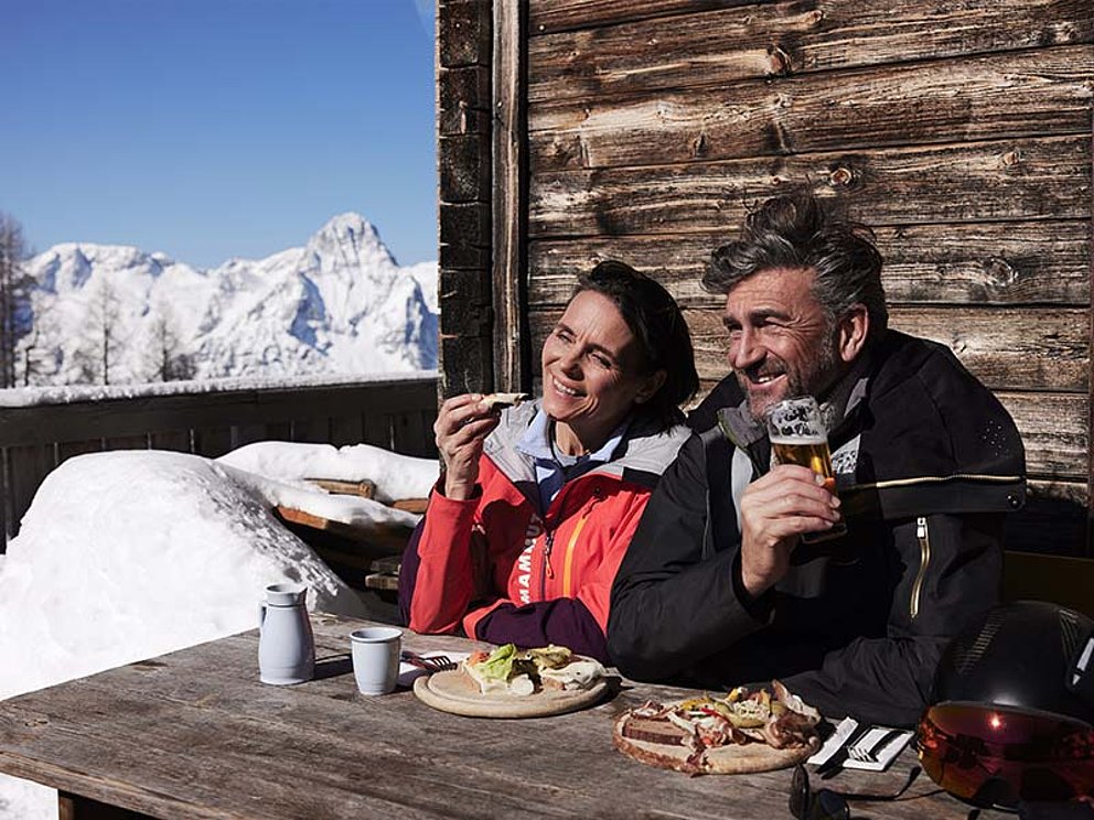 ein Paar am gedeckten Tisch auf der Terrasse einer Hütte.