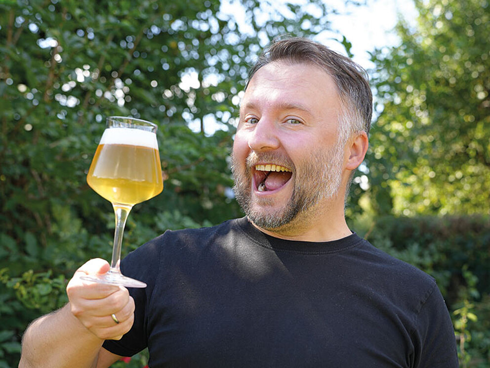 Ein motivierter Biertrinker, der sich freut, einen Schluck seines frisch gezapften Bieres zu verkosten.