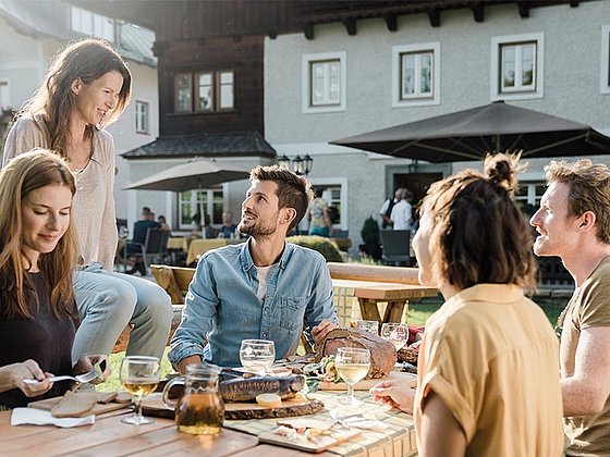 5 Personen am gedeckten Tisch in einem Gastgarten