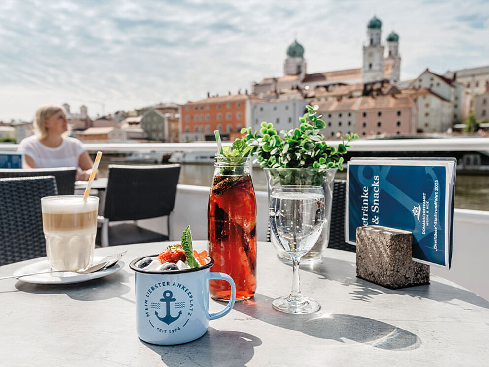 ein mit Kaffee und Saft gedeckter Tisch, im Hintergrund die Stadt Passau mit Dom