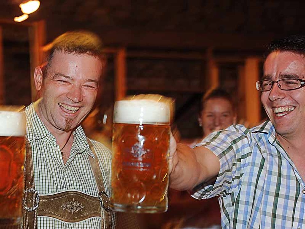 zwei Männer beim Maßkrugstemmen 