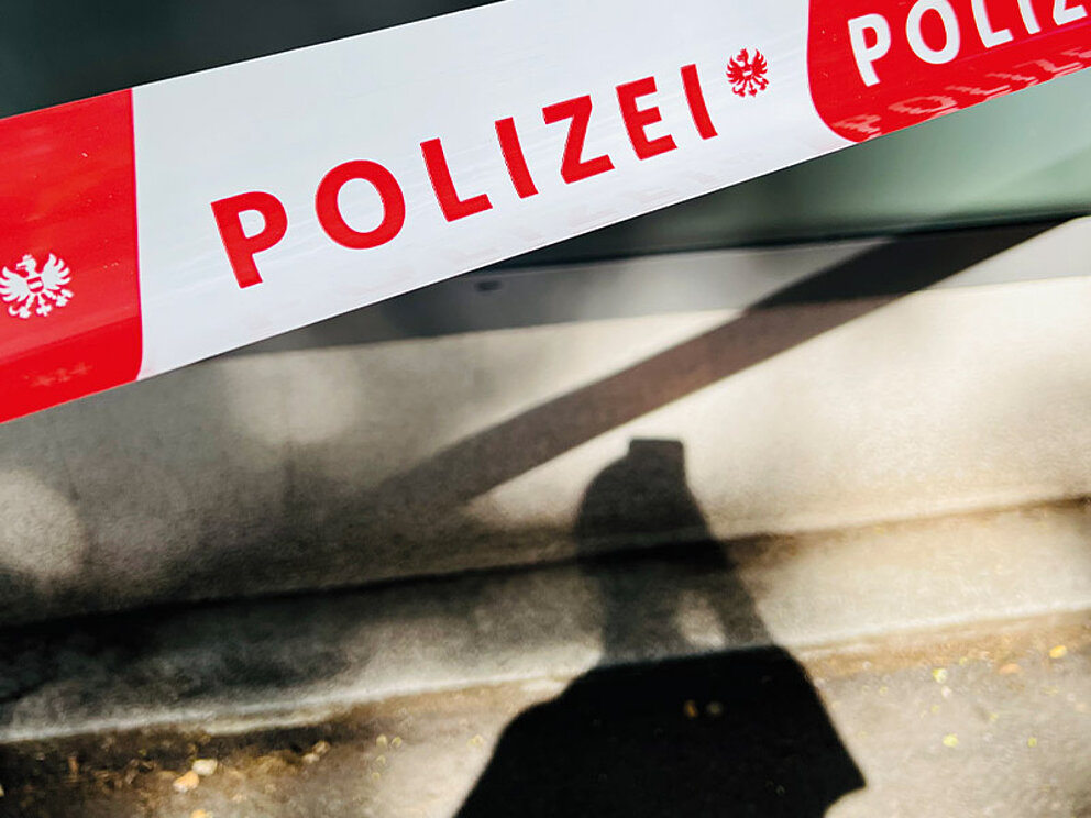 Polizeiabsperr-Band mit einem Schatten davor.