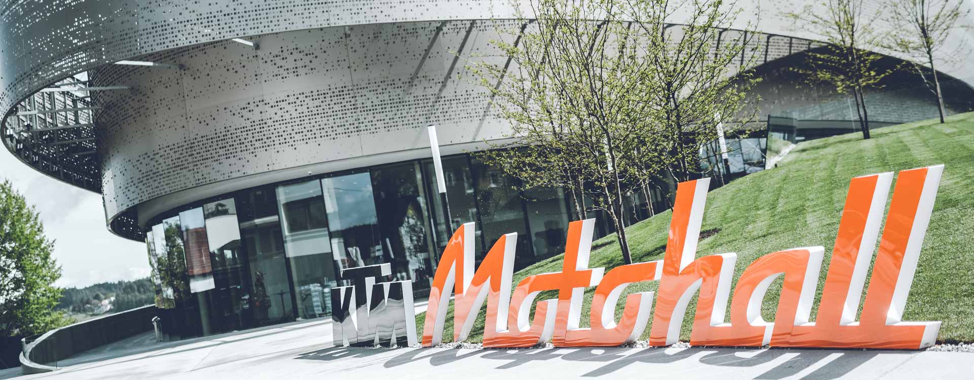 Außenansicht der Motohall mit dem großen orangen Schriftzug davor