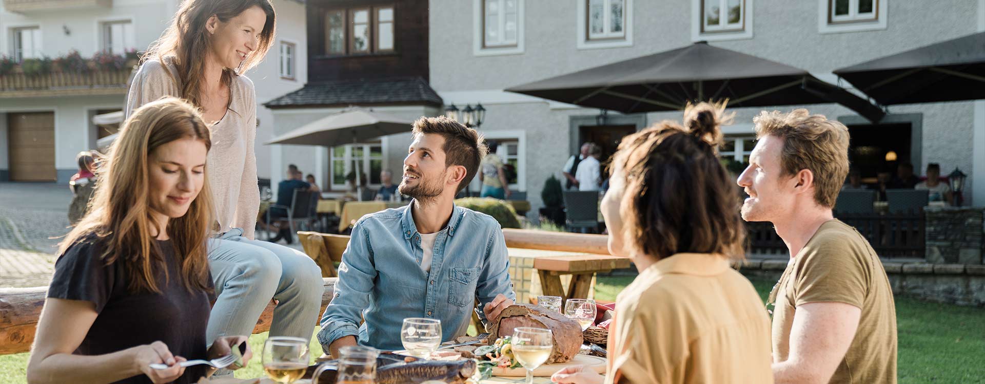 Eine Gruppe sitzt am gut gedeckten Tisch in einem Gastgarten