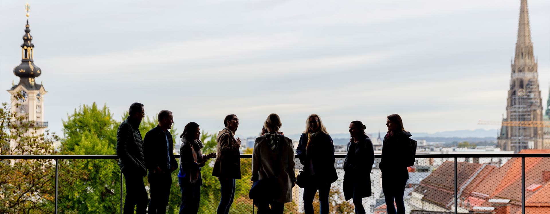 Eine Gruppe steht auf der Terrasse des LInzer Schlosses und blickt über Linz