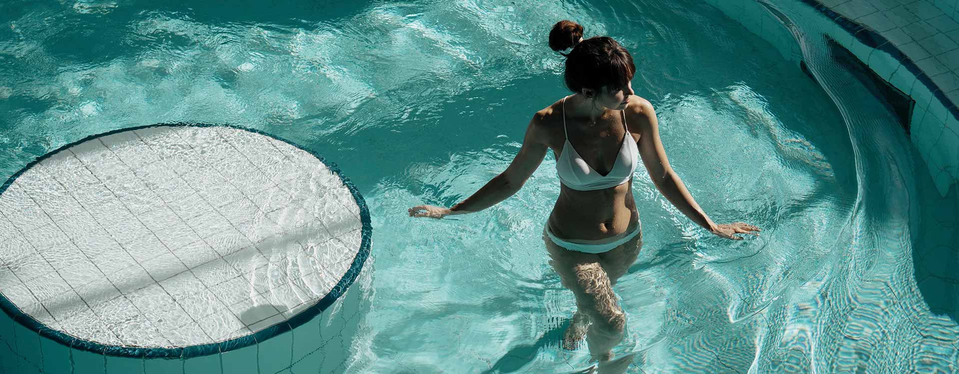 Eine Dame im türkis-blauen Thermalwasser in der Therme Geinberg