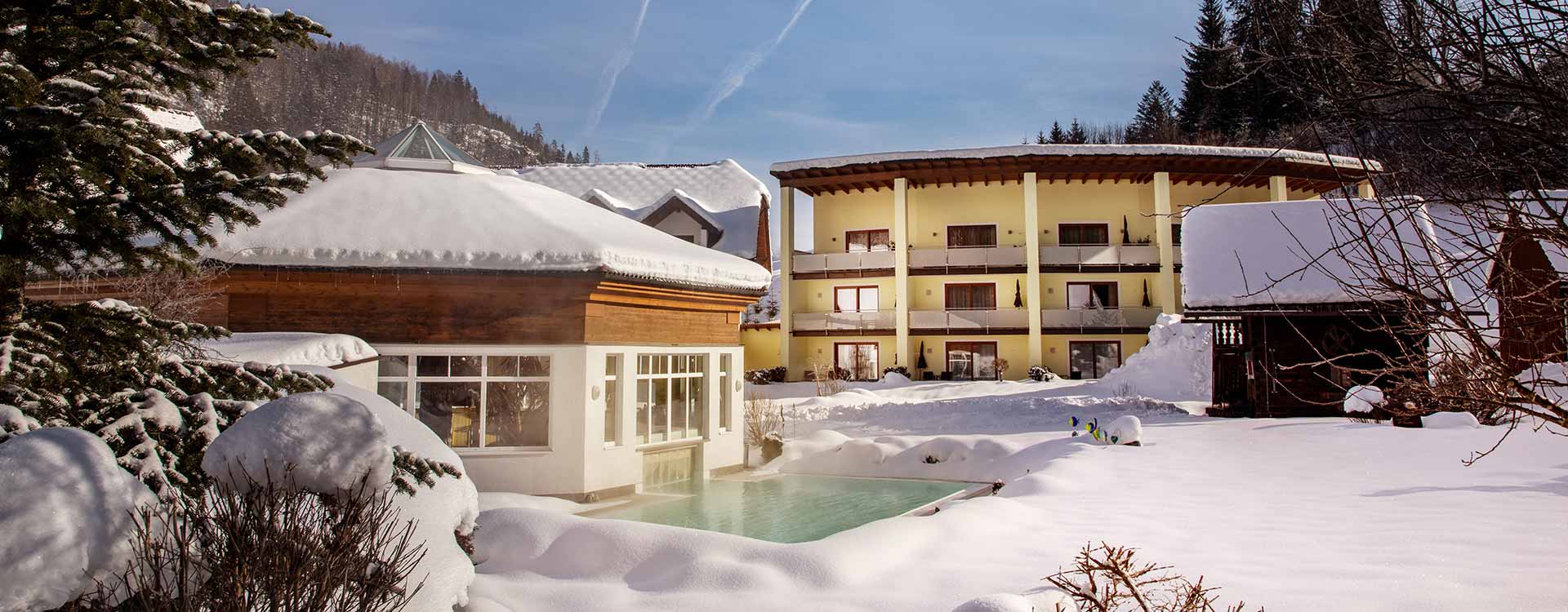 Winterliche Außenansicht des Hotels mit Outdoorpool