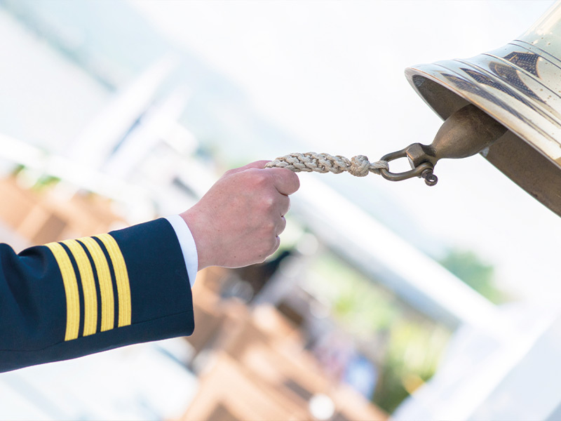 Der Arm des Kapitäns läutet die Schiffsglocke 